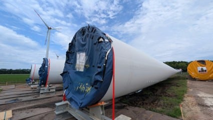 La imagen muestra varias piezas de aerogeneradores colocadas sobre el terreno.