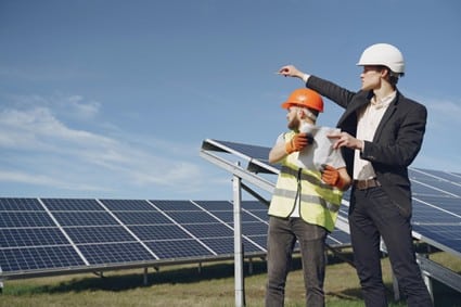 Dos hombres con casco observan un panel solar en una instalación. Evaluar el estado de estas estructuras es fundamental para garantizar la rentabilidad de la energía solar fotovoltaica instalada en España.