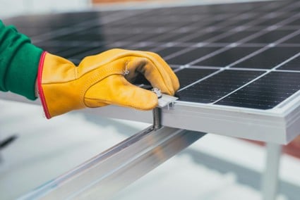 Imagen de una persona atornillando un panel de energía solar fotovoltaica en España